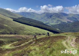 female mountain bikers descending on single trail in the scottish mountains